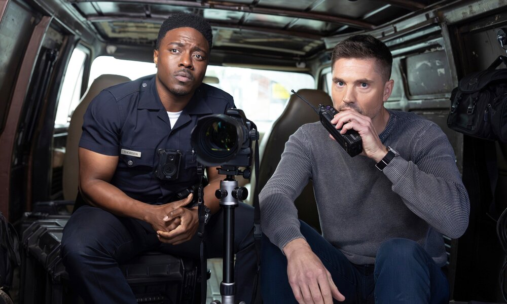 Tru Valentino in Uniform und Eric Winter in Zivil mit Sprechfunkgerät sitzen in einer Szene aus der 6. Staffel von "The Rookie" in einem Van bei einem Polizeieinsatz. | © © 2024 Lions Gate Television, Inc. And Abc Signature. All Rights Reserved.