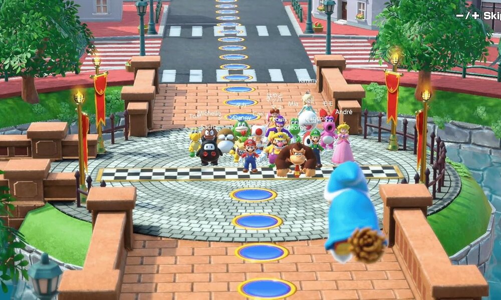 Szene aus Super Mario Party Jamboree: Verschiedene bekannte Spielfiguren wie Mario, Donkey Kong und Prinzessin Peach stehen aufgereiht auf einem Spielbrett, gepflasterten Platz vor einer Brücke. | © Amazon/Nintendo