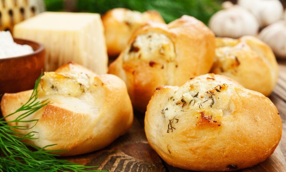 Mehrere deftige Quarkbrötchen mit Kräutern auf einer Holzunterlage in Nahaufnahme. | © Adobe Stock / minadezhda
