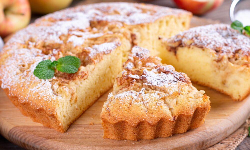 Angeschnittener Apfel-Joghurtkuchen mit Zimt und Puderzucker bestreut. | © Getty Images / 	Qwart