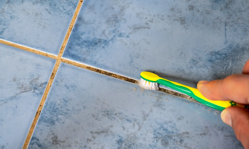 Entfernung von Schimmel aus einer Fuge im Badezimmer mit einer Zahnbürste | © adobe.stock.com/Ralf Geithe