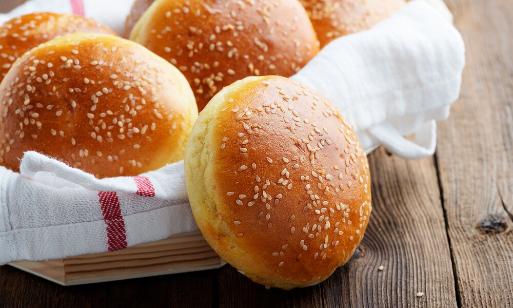 Mehrere Burgerbrötchen in einem Brotkorb mit einem Geschirrtuch innen, angerichtet. | © Adobe Stock / Nelea Reazanteva