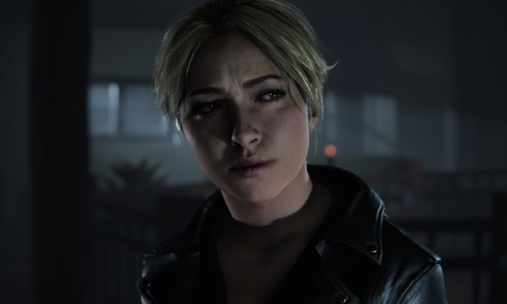 Eine blonde Frau mit skeptischem Ausdruck steht in einer düsteren Umgebung, gekleidet in eine schwarze Jacke. | © Supermassive Games / Ballistic Moon