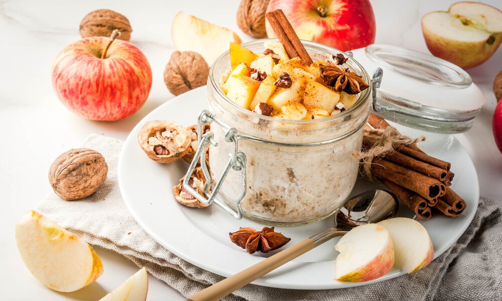 Bratapfel-Mascarpone Dessert im Glas daneben frische Äpfel und Zimtstangen. | © Getty Images / 	Rimma_Bondarenko