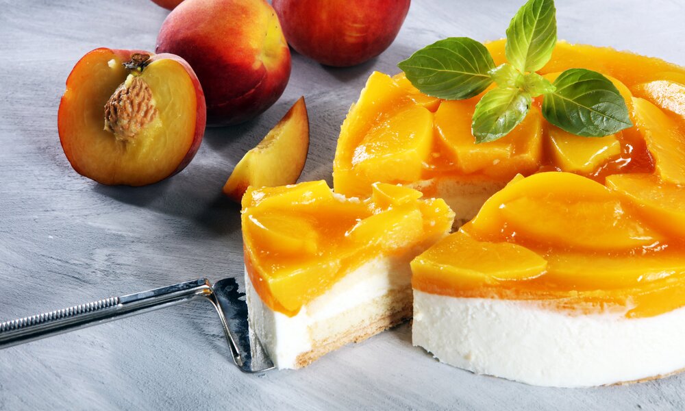 Angeschnittener Pfirsch-Schmandkuchen auf einem Kuchenteller. | © Getty Images /beats3