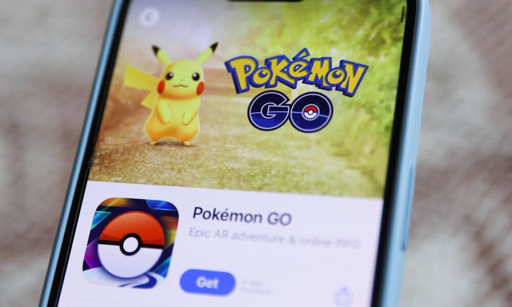 Auf einem Smartphone ist die Pokémon GO-App geöffnet, mit Pikachu und dem App-Symbol im Vordergrund. | © IMAGO / NurPhoto / Jakub Porzycki