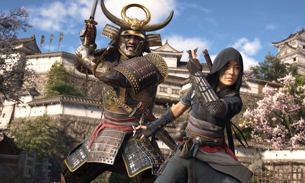 Ein Samurai mit verziertem Helm und eine Frau in dunkler Kleidung posieren vor einer traditionellen japanischen Burg, umgeben von blühenden Kirschbäumen. | © Ubisoft