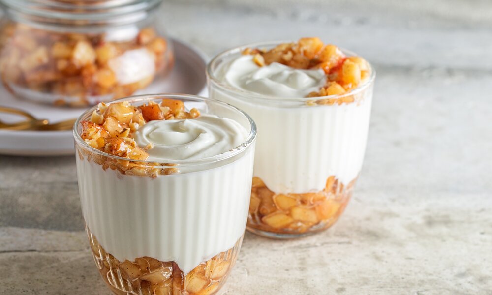 Apfel-Schichtdessert mit kleinen Apfelstücken abwechselnd geschichtet mit einer weißen Creme. | © Adobe Stock / Olga