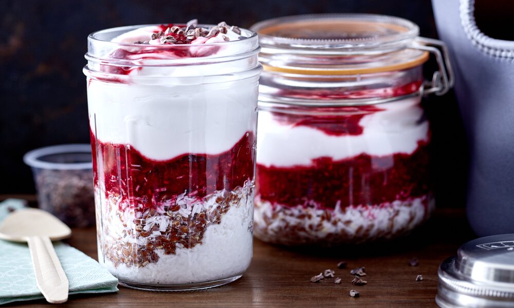 Zwei Gläser gefüllt mit einer Mixtur aus Himbeeren, Joghurt und Kokos auf einem Holzuntergrund. | © 	Johannes Reinecke