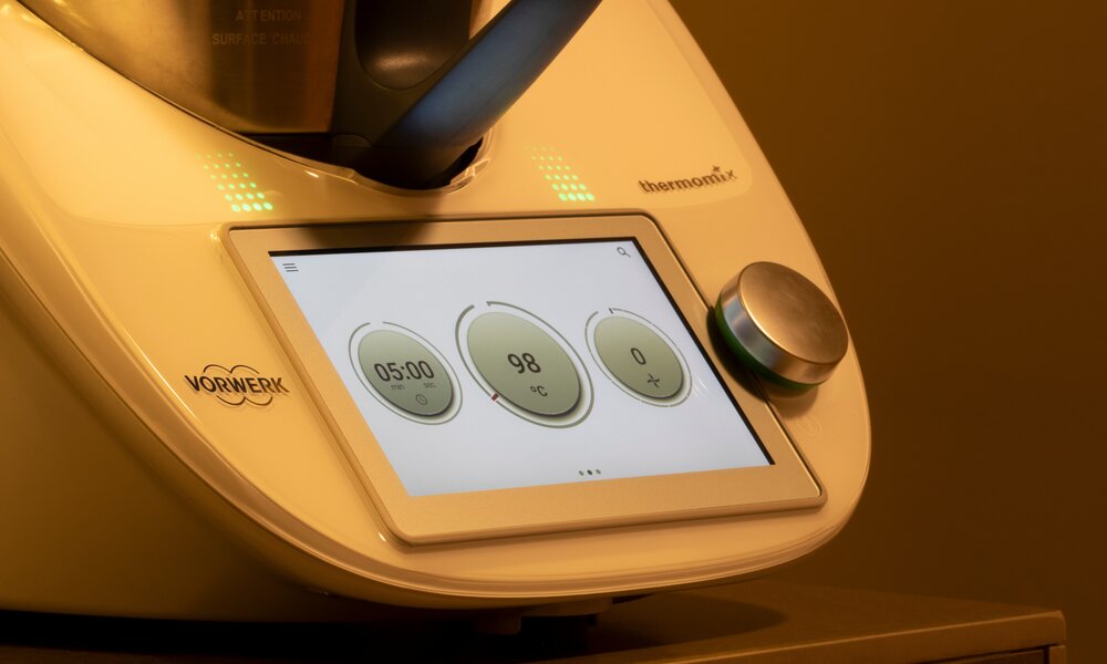 Detailansicht des Vorwerk Thermomix mit Drehknopf und einem Display, das Temperatur und Zeit für einen Kochvorgang zeigt. | © Adobe Stock/ Tada Images