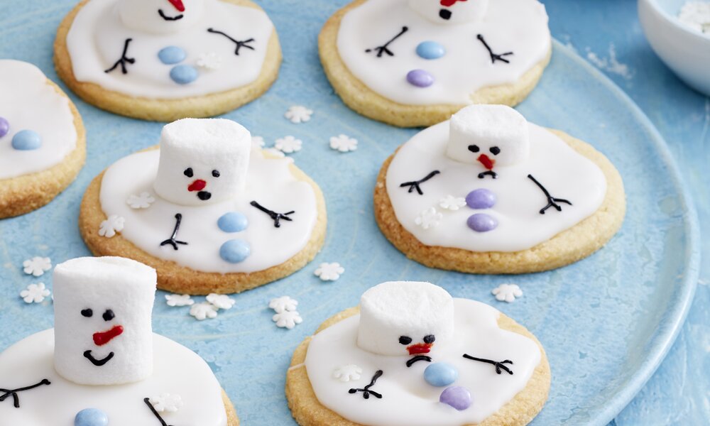 Mehrere Schneemann-Kekse mit Marshmallows auf einem Teller in blauer, winterlicher Atmosphäre. | © 	Isabell Triemer