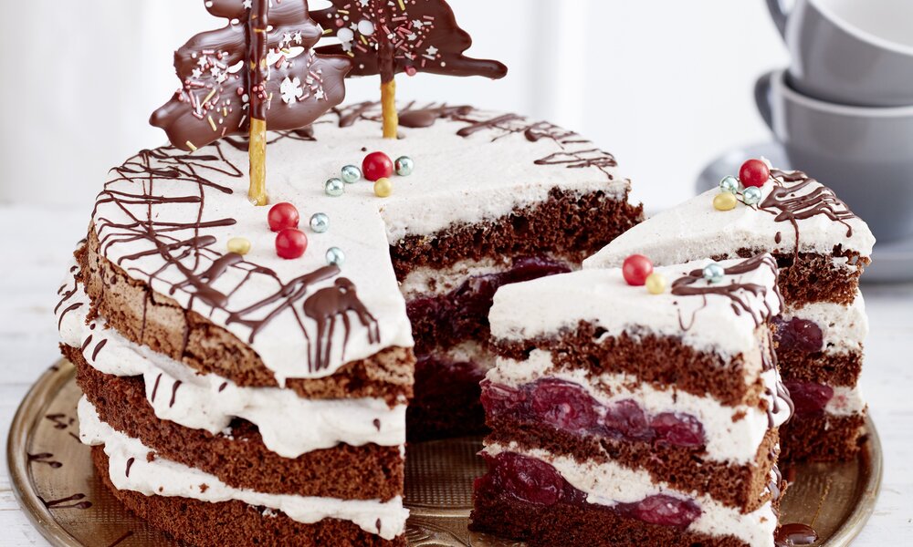 Angeschnittene Schwarzwälder Glühwein-Kirschtorte auf einem Kuchenteller, in festlicher Umgebung. | © Isabell Triemer