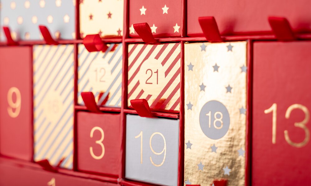 Nahaufnahme von einem roten Adventskalender mit verschiedenen nummerierten Türchen. | © Getty Images/karetoria