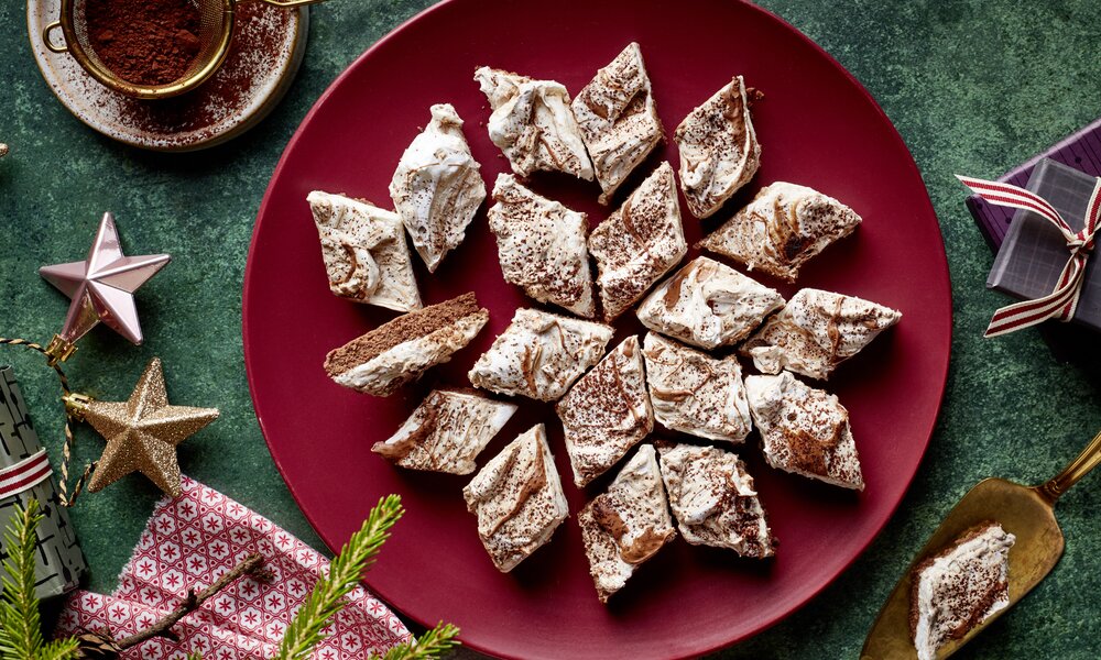 Mehrere Nougat-Baiser-Kekse auf einem Teller angerichtet in weihnachtlicher Umgebung. | ©  Isabell Triemer