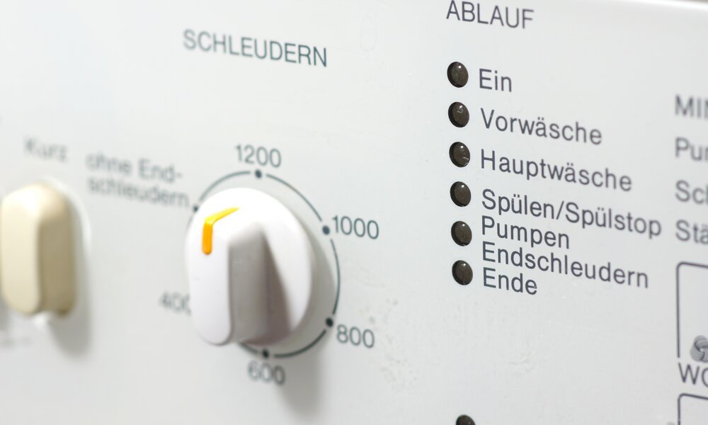 Nahaufnahme eines Waschmaschinen-Bedienfelds mit Drehregler für Schleuderdrehzahlen und Programmanzeige für verschiedene Waschstufen. | © Adobe Stock/ PhotographyByMK