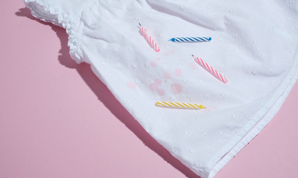 Wachsflecken von Geburtstagskerzen auf weißem Kleid | © Adobe Stock/ HalynaRom