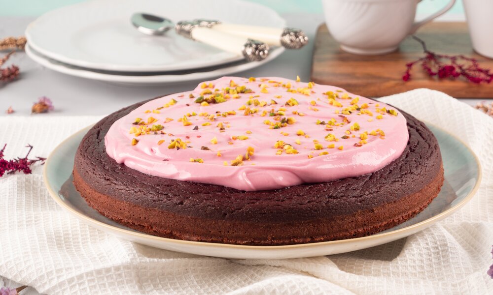 Rote Bete Kuchen mit rosa Frosting auf einem Tisch mit Besteck und. | © Adobe Stock / tenkende