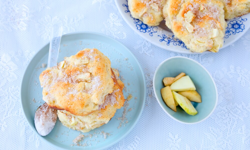 Apfel-Bällchen auf einem Teller, daneben frische Apfelscheiben und weitere Apfel-Bällchen, alles in blau gehalten. | © Adobe Stock / rainbow33