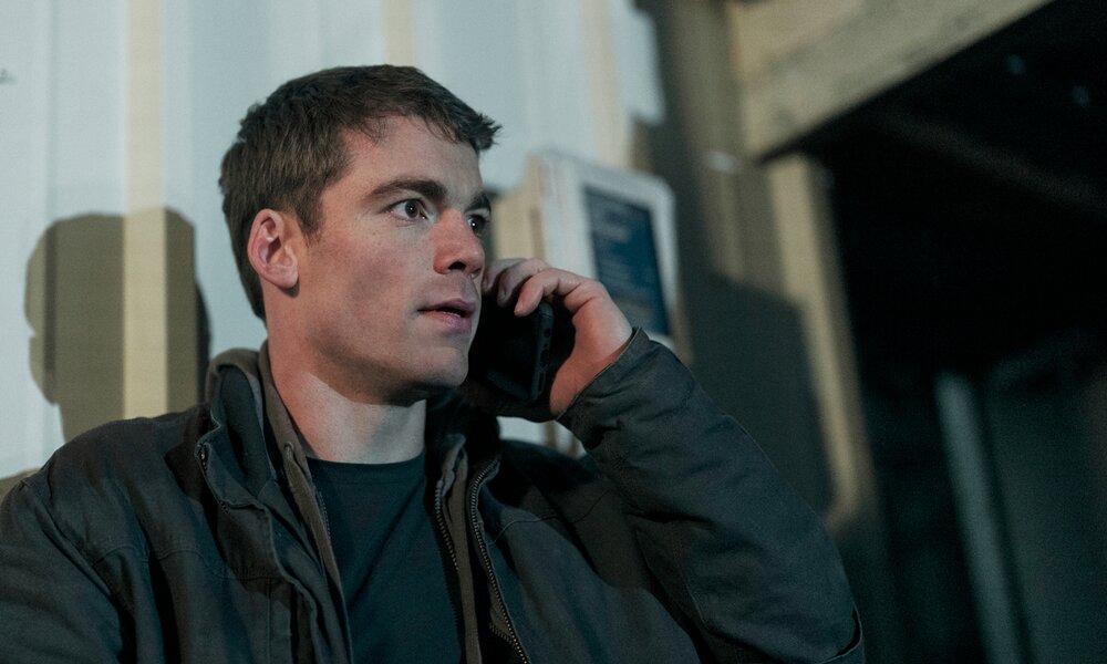 Gabriel Basso als FBI-Agent am Telefon nachts auf der Straße in einer Szene aus der 2. Staffel der Netflix-Serie "The Night Agent" | © Netflix/ Christopher Saunders