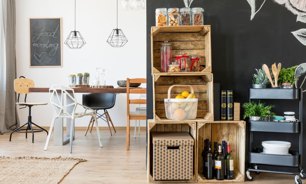 Helles Interieur mit Essplatz, Glaspendelleuchten, Deko aus Holz und Metall sowie Regalen voller Gläser, Obst und Weinflaschen. | © Photographee.eu / stock.adobe.com