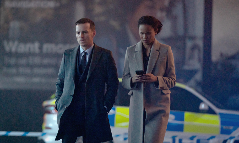 Andrew Scott und Fola Evans-Akingbola laufen in einer Szene aus dem Netflix-Film "Back in Action" nachts auf einer Straße, im Hintergrund ein Polizeiauto | © Netflix/Matt Towers