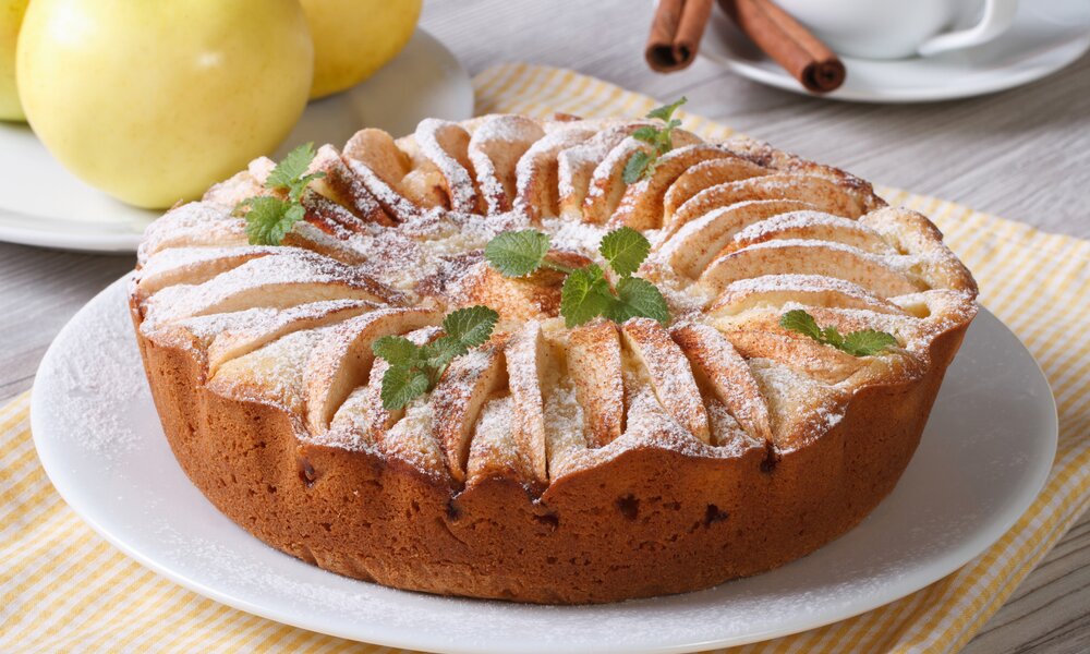 Luftiger Apfel-Quarkkuchen auf einem Holztisch. | © Getty Images / ALLEKO