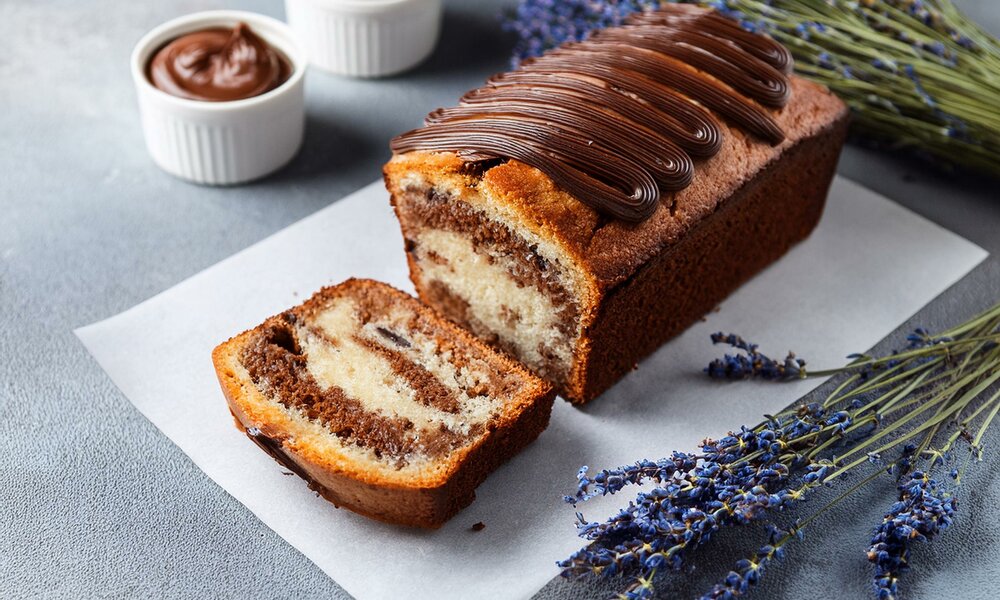 Angeschnittener Nutella-Kuchen in Kastenform auf einem Holzuntergrund, daneben Nutella und Lavendel. | © Adobe Stock / Jeri / KI generiert
