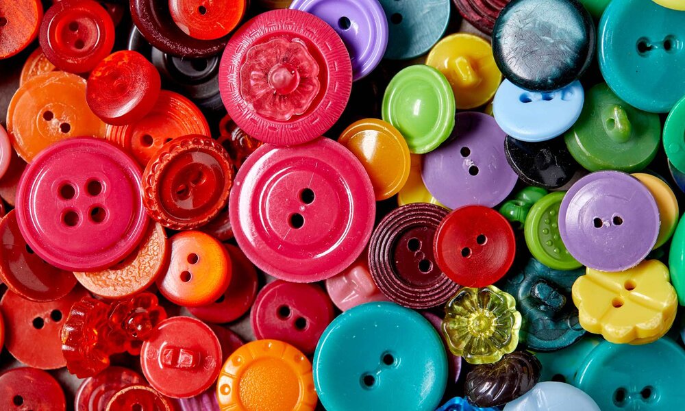 Bunte Sammlung verschieden großer Knöpfe in Rot-, Grün-, Blau- und Gelbtönen, teils glänzend, auf eng liegendem Hintergrund. | © fox17/stock.adobe.com
