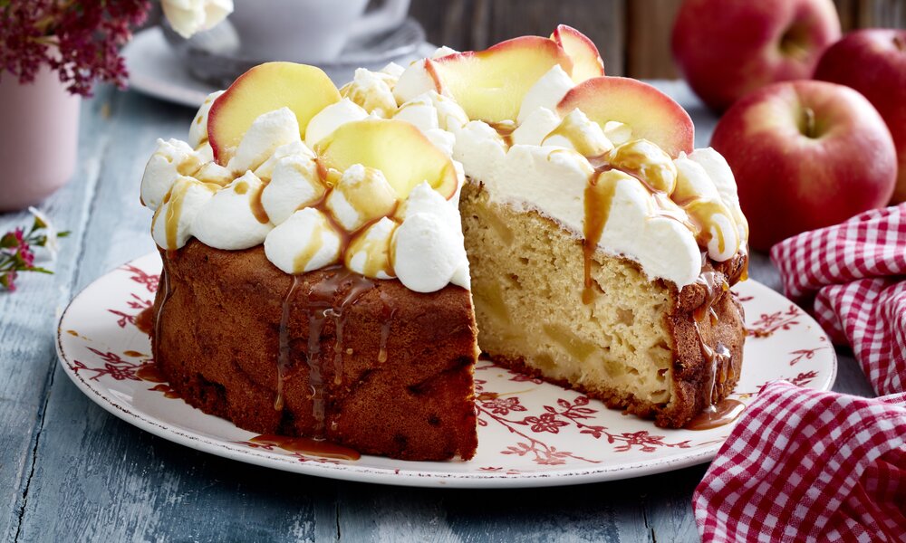 Angeschnittene Apfel-Creme-Torte mit Apfelstücken und Karamellsoße. | © Isabell Triemer