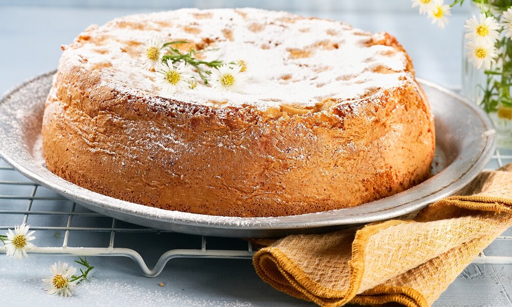 Ganzer Zitronenkuchen in frühlingshafter Umgebung angerichtet. | © Getty Images / Mila Bond