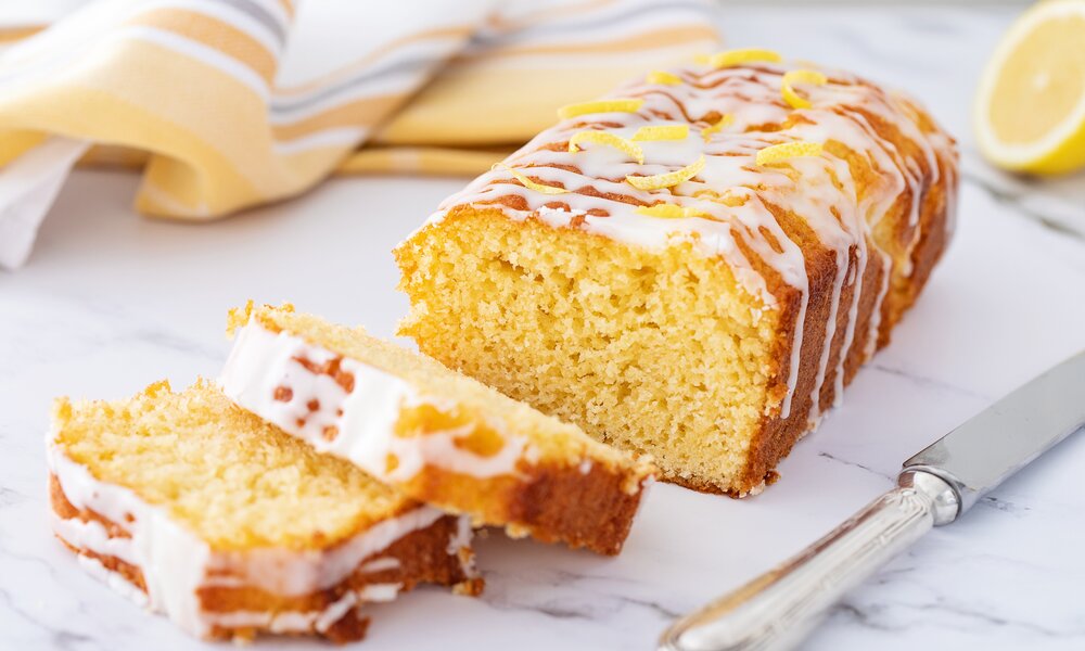 Angeschnittener Zitronenkuchen mit Zitronenkuss auf einem Kuchengitter. | © Getty Images / Cris Cantón