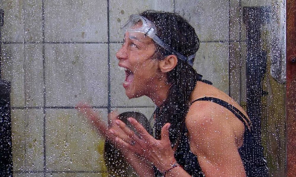 Lilly Becker mit Schutzbrille schreit mit weit aufgerissenem Mund in einer nassen, gefliesten Duschkabine. | © RTL