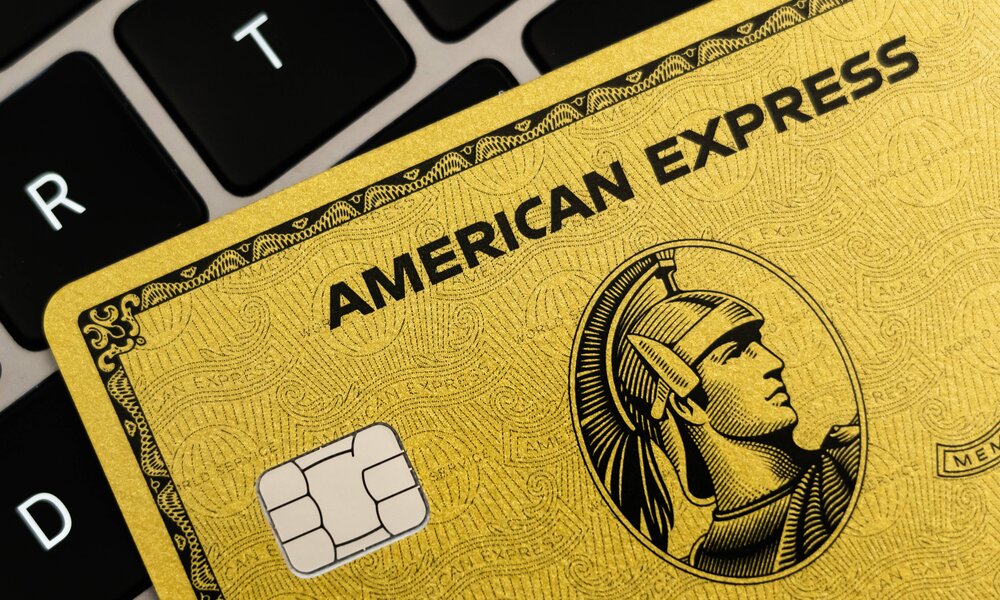 Eine goldene American Express Kreditkarte mit Chip liegt schräg auf einer schwarzen Laptop-Tastatur. | © IMAGO/Silas Stein
