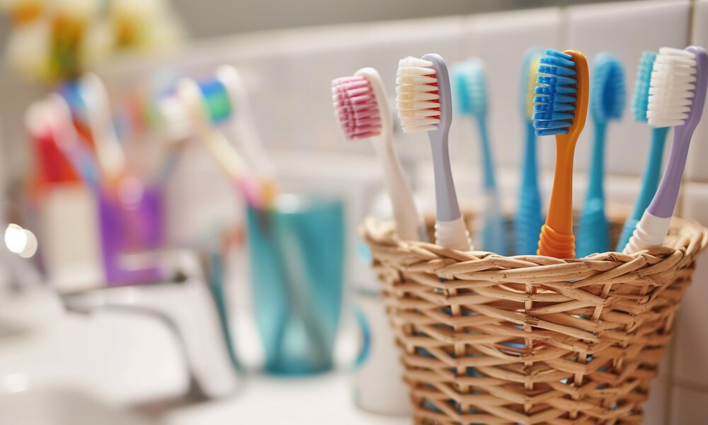 badezimmer, neben waschbecken steht ein becher mit vielen bunten zahnbürsten | © Adobe Stock/Iryna