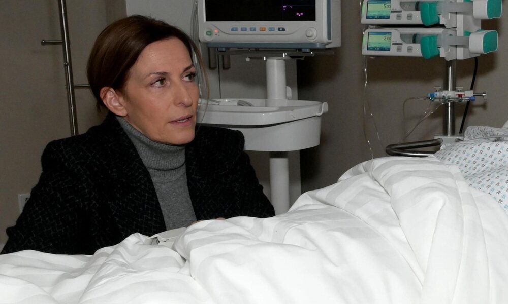 Eine Frau mit braunen Haaren und dunklem Blazer sitzt besorgt an einem Krankenhausbett mit medizinischen Geräten im Hintergrund. | © RTL / Rolf Baumgartner