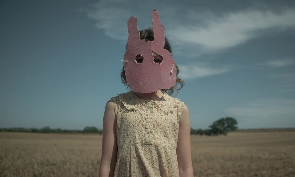 Zu sehen: Ein Mädchen mit Hasenmaske auf einem Feld, Bild aus dem Netflix-Psychothriller "Run Rabbit Run". | © Netflix