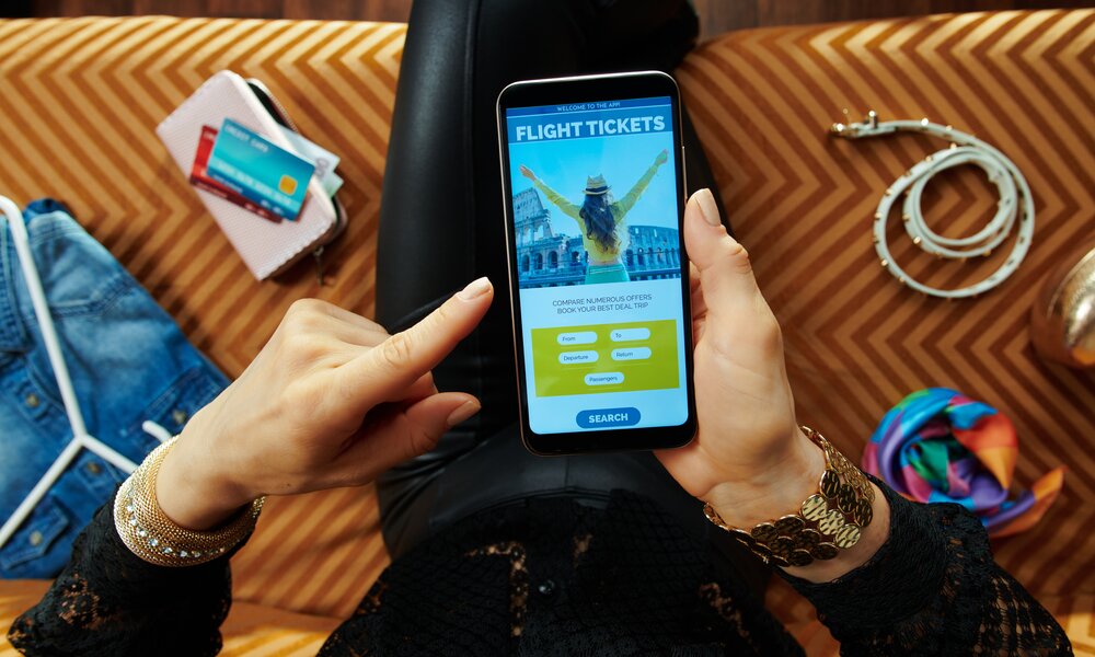 Frau bucht Flug über Handy | © gettyimages / CentralITAlliance
