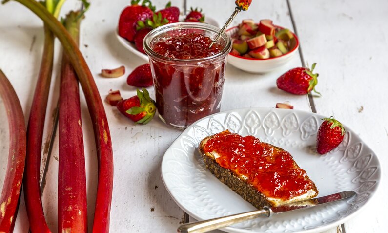 Frische Erdbeeren und Rhabarber liegen neben Marmeladenbrot auf Teller | © gettyimages / Westend61