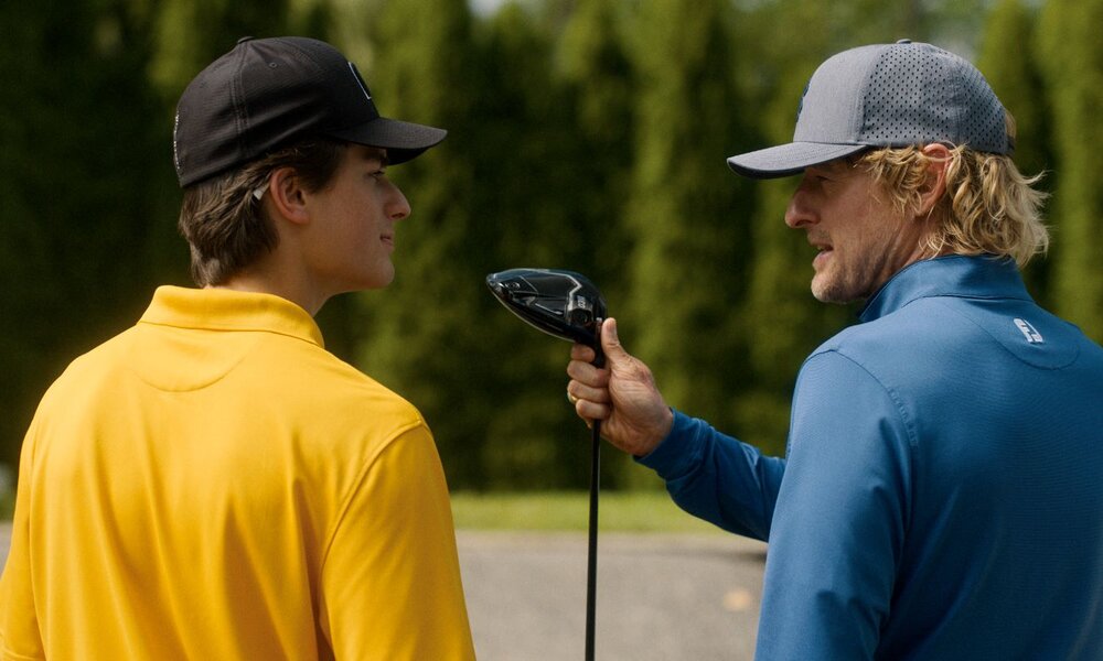 "Der Pryce ist heiß" steht auf der Visitenkarte von Ex-Profi Pryce Cahill (Owen Wilson, rechts): Davon will er nun seinen Schützling Santi (Peter Dager) überzeugen. | © Apple TV+