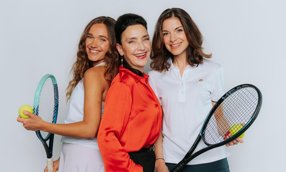 Zwei sportlich gekleidete Frauen mit Tenniszubehör und eine elegant gekleidete Frau lachen gemeinsam in die Kamera. | © RTL / Julia Feldhagen
