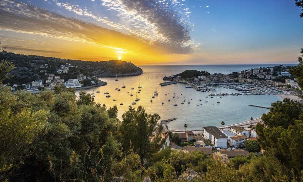 Blick auf eine idyllische Hafenbucht mit vielen Segelbooten im goldenen Licht eines dramatischen Sonnenuntergangs über dem Meer. | © HR / Joel Hess
