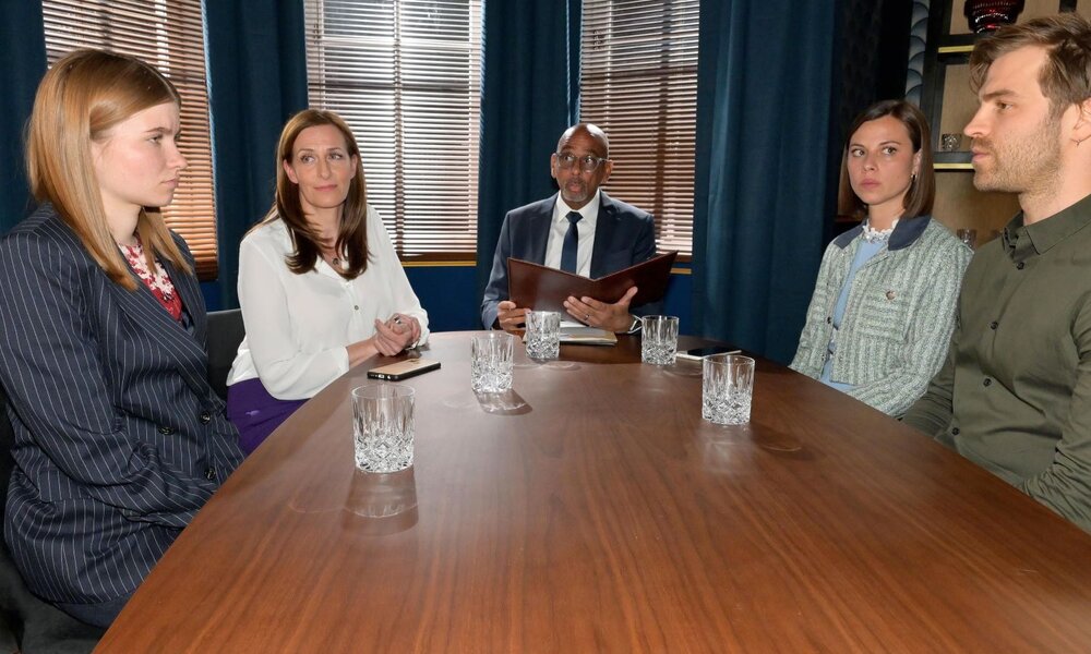 Fünf ernste Erwachsene sitzen sich an einem Konferenztisch gegenüber, inmitten von Gläsern und Aktenmappe vor blauen Vorhängen. | © RTL / Rolf Baumgartner