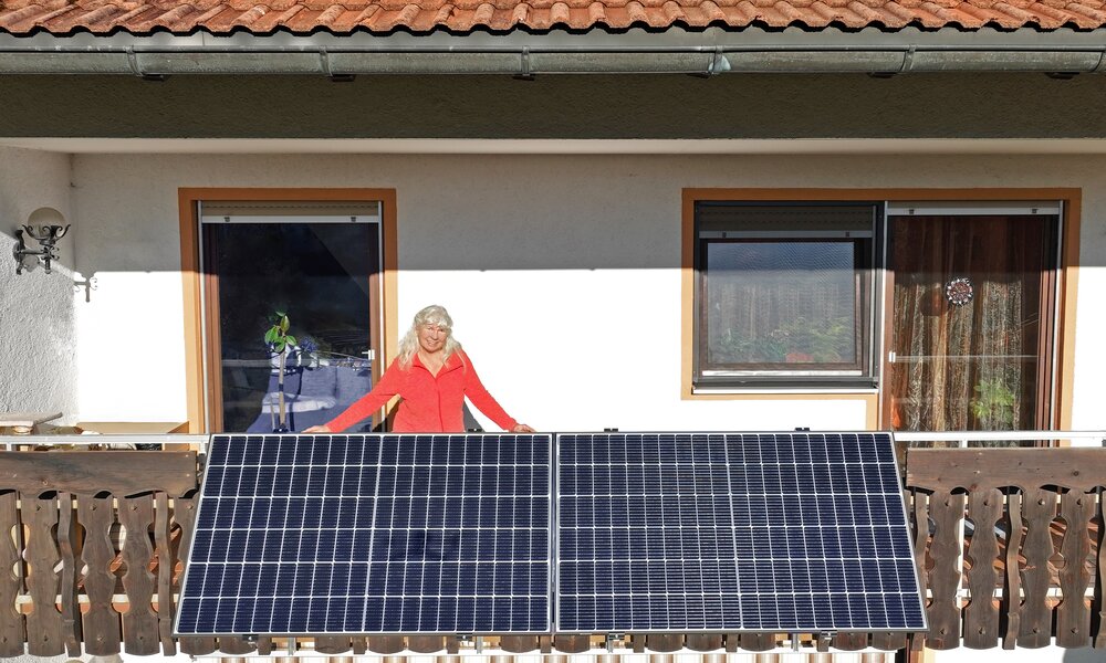 Frau auf Balkon mit Solaranlage | © Getty Images/Astrid860