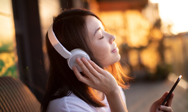 Frau mit Kopfhörern in einer gut gelaunten Stimmung | © Getty Images / Oscar Wong