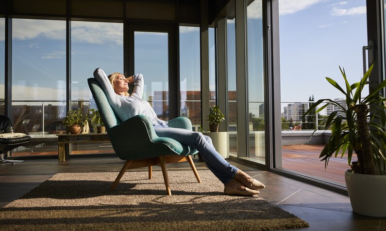Frau relaxt auf Sofa vor Fenster | © Getty Images / Westend61