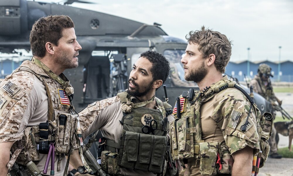 David Boreanaz und zwei Kollegen stehen in einer Szene in der CBS-Serie "Seal" vor einem Hubschrauber. Sie tragen alle die komolette Ausstrattung für einen Einsatz und diskutieren miteinander. | © 2017 CBS Broadcasting, Inc. All rights reserved