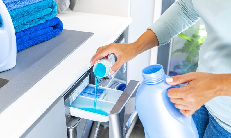 Flüssiges, blaues Waschmittel wird in die Öffnung einer Waschmaschine gegossen | © Getty Images / fcafotodigital