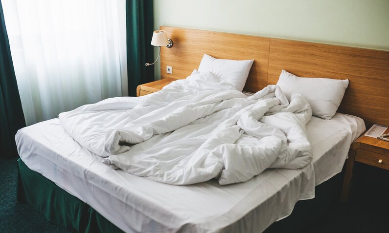 Zerwühltes Hotelbett mit weißer Bettwäsche | ©  Getty Images / franz12