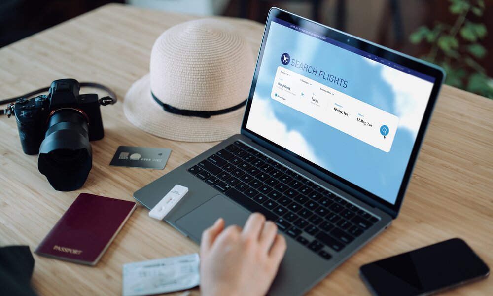Ein Mann hat am Laptop ein Reiseportal geöffnet. Um ihn herum liegen Ausweisdokumente.  | ©  Getty Images / d3sign