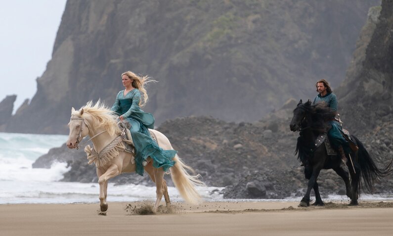 Morfydd Clark als Galadriel und Lloyd Owen als Elendil reiten über einen Strand in einer Szene der Prime Video Serie "Der Herr der Ringe: Die Ringe der Macht§ | © Amazon Studios/Prime Video